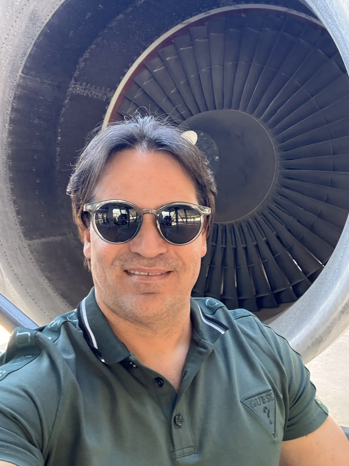 Selfie de Ivaldo, de óculos escuros e camisa polo verde, diante da enorme turbina de um avião em exposição no Space Center Houston